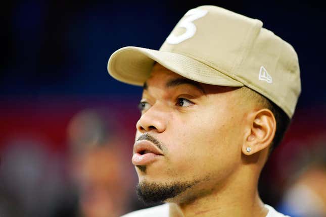 A close-up shot of Chance the Rapper from the side, wearing a tan baseball cap. 