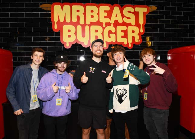 (L-R) Nolan Hansen, Sapnap, MrBeast, Karl Jacobs and Punz (all social media influencers) stand in front of a "MrBeast Burger" sign on a black tiled wall.